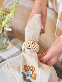 a person is holding a napkin with beaded flowers on it and placing beads on the napkin