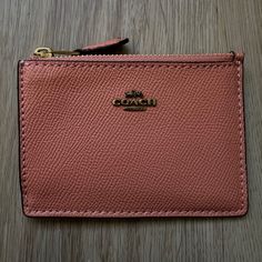 a pink coach wallet sitting on top of a wooden table