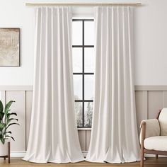 a white curtain hanging in front of a window next to a chair and potted plant