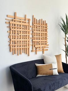 a couch with pillows and two wooden wall art pieces on the wall next to it