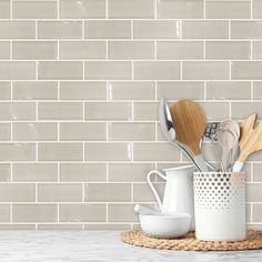 kitchen utensils and wooden spoons are sitting on a countertop in front of a white brick wall