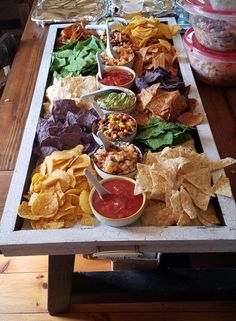 a tray with chips, guacamole and salsa dips is on the table