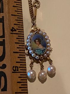 Estate Fresh! This is a beautiful Reverse Portrait On Glass Pendant Hanging From a Bracelet Chain . Victorian Portrait Is Surrounded By Pearls And 3 Dangle Pearls. Reverse painted portraits art reigned from about 1815 to 1850. Then, with the exception of a brief time before WW I when it enjoyed a comeback, reverse glass painting became all but extinct. Please remember all items are vintage & estate found, therefore do not expect perfection as they may show some wear or imperfections only add Artistic Gold Jewelry With Vintage Charm, Reverse Glass Painting, Victorian Portrait, Grandma Vintage, Scorpio Necklace, Painted Portraits, Victorian Portraits, Portraits Art, Rhinestone Jewelry Set