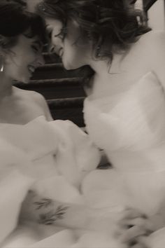 two women in white dresses looking at each other