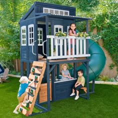 two children playing in a play house with a slide and climbing frame on the grass