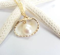 Beautiful gold sea shell necklace made with a gold plated seashell charm with a gold filled chain and fresh water pearl. This necklace makes a unique gift for a beach lover or someone special in your life. The seashell is around 15- 20mm long. Each item is carefully packaged in a beautiful jewellery box ready as a gift. If you would like to add a personalized note with your order, just write a note at checkout and I will send a small card with your gift to the recipient. Please choose necklace l Beach Jewelry With Pearl Pendant In Shell Shape, Shell-shaped Pearl Pendant Jewelry For Beach, Ocean-inspired Pearl Pendant Necklaces As Gifts, Pearl Pendant Shell As Gift, Elegant Pearl Pendant Shell For Beach, Elegant Beach Pearl Shell Pendant, Strand Shell Necklace With Pearl Charm As Gift, Pearl Charm Shell Necklace Gift, Pearl Charm Shell Necklace As Gift