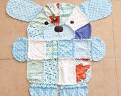 a teddy bear made out of baby's quilts on the floor with its eyes closed