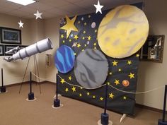 a space themed wall in an office with two telescopes and planets on the wall