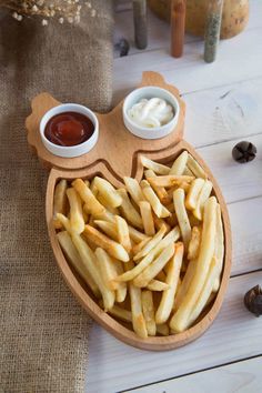 a wooden plate with french fries and dipping sauce