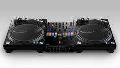 two turntables sitting next to each other on top of a black table with dj controllers