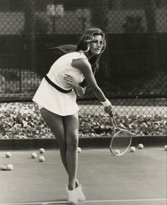 a woman holding a tennis racquet on top of a tennis court with balls in the background