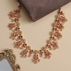 Description An array of crescents and flower petals are decorated with pink Kempu, Polki stone and inlaid green stones. This exquisite Jadau necklace is finished with tiny pearl clusters; a charming addition to any event attire. Product Information Materials used: 925 Silver with 1.0-microns Gold Plating Stones: Semi-precious stones Length: 15 cm & adjustable Findings: Hook & links Luxury Multicolor Temple Necklace With Cutdana, Poosalu Necklace, Necklace Set Indian Bridal Jewelry, Event Attire, Jadau Necklace, Neck Pieces Jewelry, Antique Necklaces Design, Designers Jewelry Collection, Fancy Jewelry Necklace