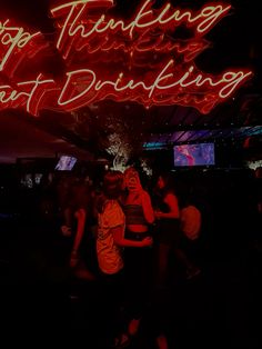 people are dancing in the dark with neon signs above them that say stop thinking about drinking