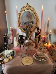 a table topped with lots of candles next to a mirror and other items on top of it