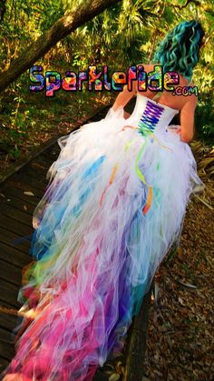 a woman wearing a colorful dress sitting on a wooden bench in the woods with her back turned to the camera