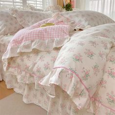 a bed with pink and white floral comforter on it's side, next to a window