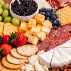 an assortment of cheeses, crackers, fruit and nuts on a platter