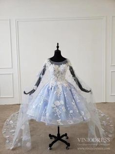 - Fairy style short prom dress with cape train - Detailing with 3D flowers and beading - Beaded bodice - Knee length dress with cathedral length cape - Built-in Bra - Back detail: Zipper Light Blue Princess Dress, Prom Dress Baby Blue, Fairytale Clothes, Princess Dress Drawing, Quinceanera Blue, Princess Dress Short, Extra Dresses, Cloud Dress, Blue Wedding Guest Dresses