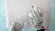 a person in white gloves holding up a clear tube with something on it's side