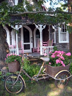 a bicycle parked in front of a house with flowers growing out of the back tire