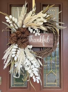 a wreath with the words, thank you and white flowers hanging from it's front door