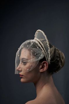 a woman wearing a veil with pearls on it and a headpiece in her hair