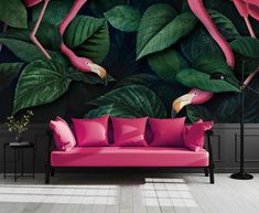 a pink couch sitting in front of a wall mural with flamingos and green leaves