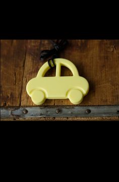 a yellow plastic toy car sitting on top of a wooden table next to a black cord