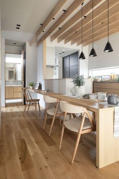 a modern kitchen with wooden floors and white walls, along with an island table that has chairs around it