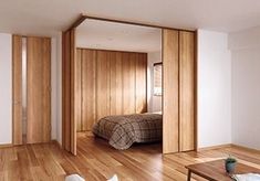 a living room with wood floors and sliding doors leading to a bed in the corner