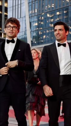 two men in tuxedos are walking down the red carpet