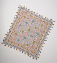 a crocheted square with pom - poms on it