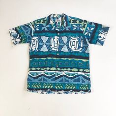 "1950's Hawaiian bark cloth shirt has a button front with silver Greek coin style buttons, and a chest pocket. Label is Andrade Resort Shops Waikiki. Made in Hawaii. Condition Excellent overall, has a faint small stain at the bottom of the pocket. Measurements Chest 44\" Waist 42\" Shoulder 18\" Sleeve length 10\" Length 28\" Best for a size medium." Retro Button-up Hawaiian Shirt, Vintage Blue Collared Camp Shirt, Retro Blue Camp Shirt With Vintage Print, Retro Blue Button-up Hawaiian Shirt, Vintage Blue Collared Hawaiian Shirt, Retro Blue Collared Hawaiian Shirt, Vintage Blue Cotton Camp Shirt, Vintage Cotton Collared Hawaiian Shirt, Blue Retro Hawaiian Button-up Shirt