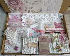 an open box filled with lots of different types of fabric and papers on top of a table