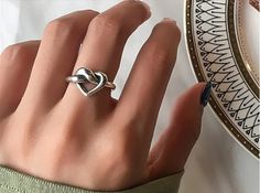 a woman's hand with a heart shaped ring on it