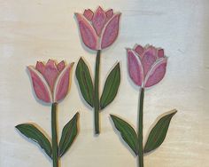 three pink flowers with green leaves on a white background are shown in the shape of cutouts