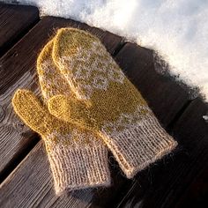 a pair of yellow mittens sitting on top of a wooden table covered in snow