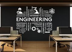 there are two computers on the desks in front of this wall decal that says engineering