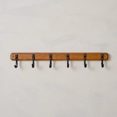 a wooden coat rack with four black hooks