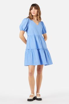 Blue mini smock dress, with a sweet v neckline. Featuring a two tier skirt, short puff sleeves & made of a cotton viscose blend. - slip on this easy relaxed style smock- soft v neckline with a sweet puff sleeve- mini length featuring a tiered skirt with exposed ruffle- handy side pocket- elastic hem on sleeve- side ties to cinch in at waist- made of a smooth viscose cotton blend- available in cornflower Product Code: PGFY141