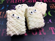 two cookies with googly eyes on them sitting on a black tablecloth covered in white frosting