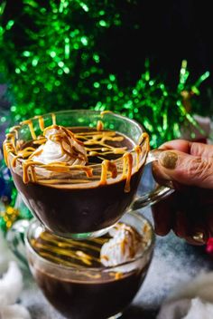 someone is holding a spoon in a glass cup filled with hot chocolate and marshmallows