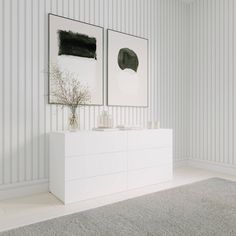 a white dresser sitting next to a wall with two pictures on it