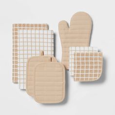 three oven mitts and one pot holder in beige with white checkered squares on them