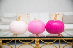 three pumpkins sitting on top of a glass table in front of a white couch