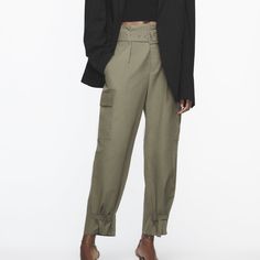 High Waisted Pants With Front Pleats And Self Belt. Front Pockets And Side Flap Patch Pockets. Adjustable Hem With Straps. Front Zip And Metal Hook Closure. Khaki 8277/411 Fall Utility High Waist Pants, High Waist Utility Pants For Fall, Fall High Waist Utility Pants, Fall High-waist Utility Pants, Khaki Ankle-length Pants With Belt Loops, Chic Cargo Pants With Belt Loops, Trendy Fall Ankle-length Parachute Pants, High-waisted Parachute Pants With Belt Loops For Work, High-waisted Cargo Pants For Fall