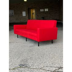 a red couch sitting in an empty parking lot