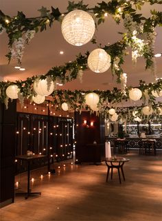 some lights hanging from the ceiling in a room with wooden flooring and greenery