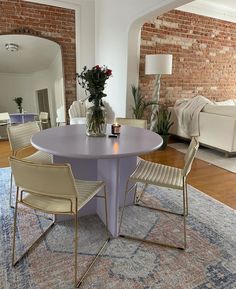 a round table with chairs around it in a living room next to a brick wall