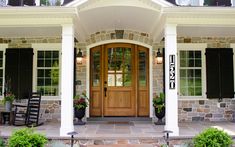 the front entrance to a home with two chairs and flowers on the steps leading up to it